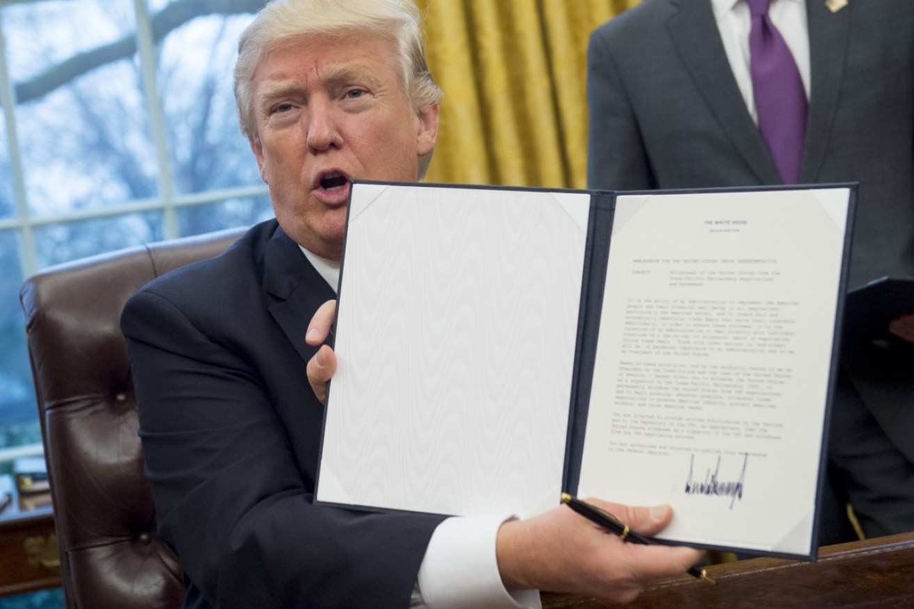 US President Donald Trump holds up the executive order withdrawing the US from the TPP. 