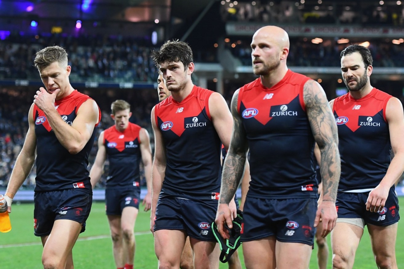 Melbourne walk off the ground after its loss to Geelong after the siren. 