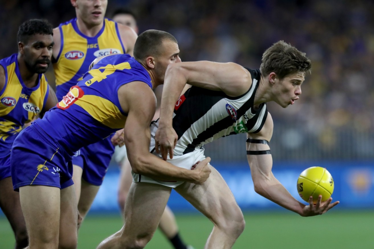 Collingwood's Josh Thomas passes under pressure from West Coast players.