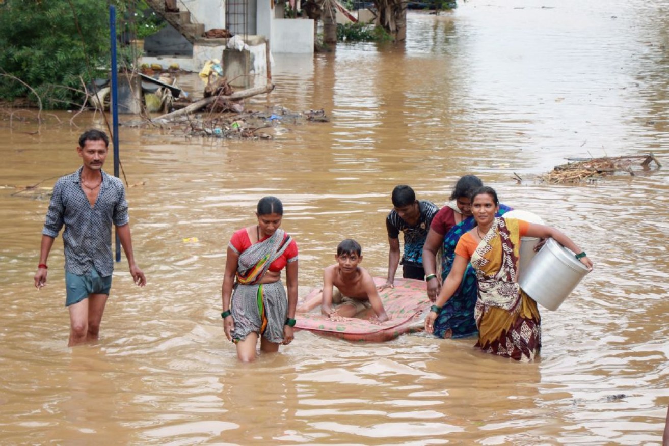 People wade through floodwaters to reach higher ground in Bagalkot District in northern Karnataka state