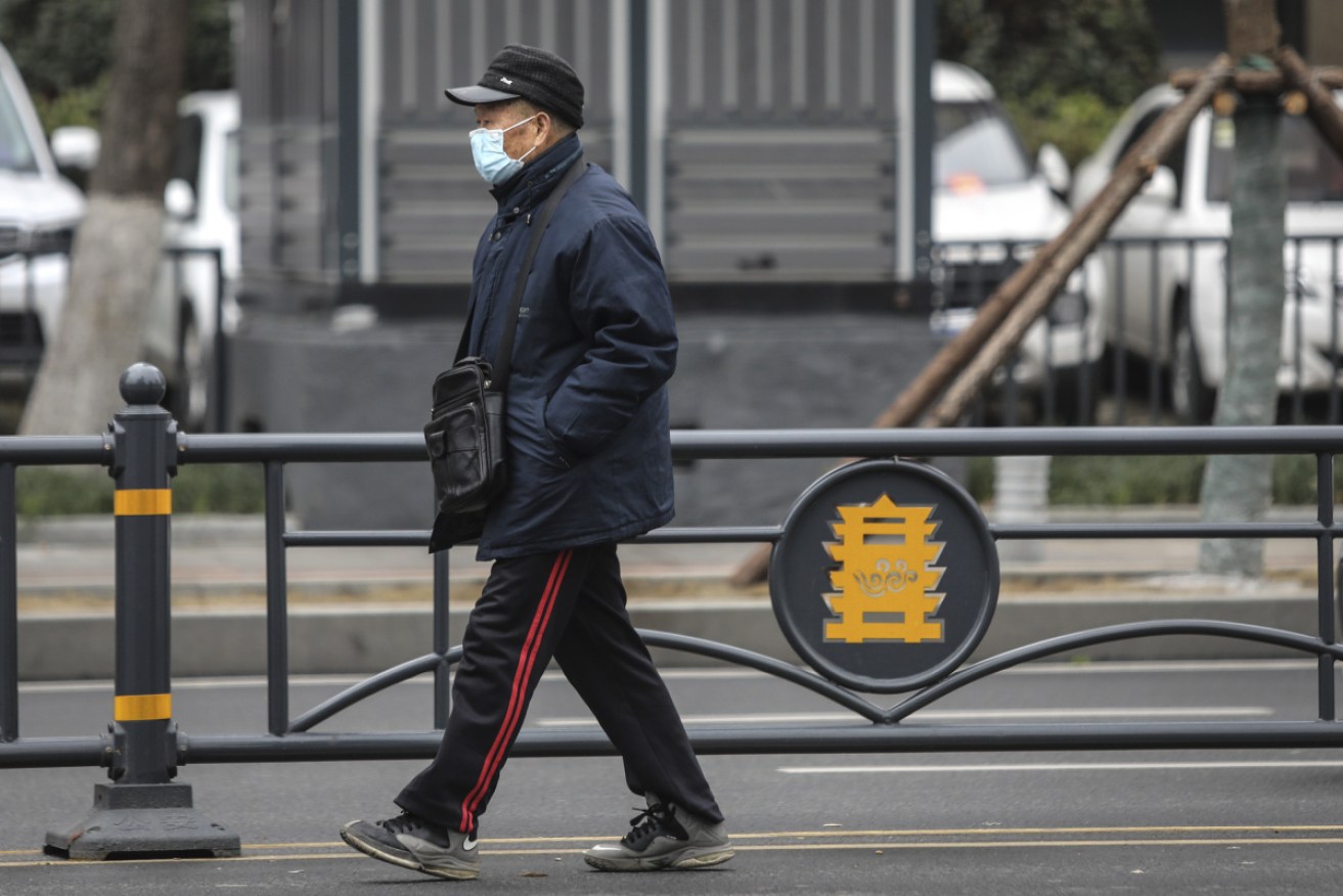 A masked man walking past the closed Huanan Seafood Wholesale Market, which has been linked to cases of coronavirus in Wuhan, China. 