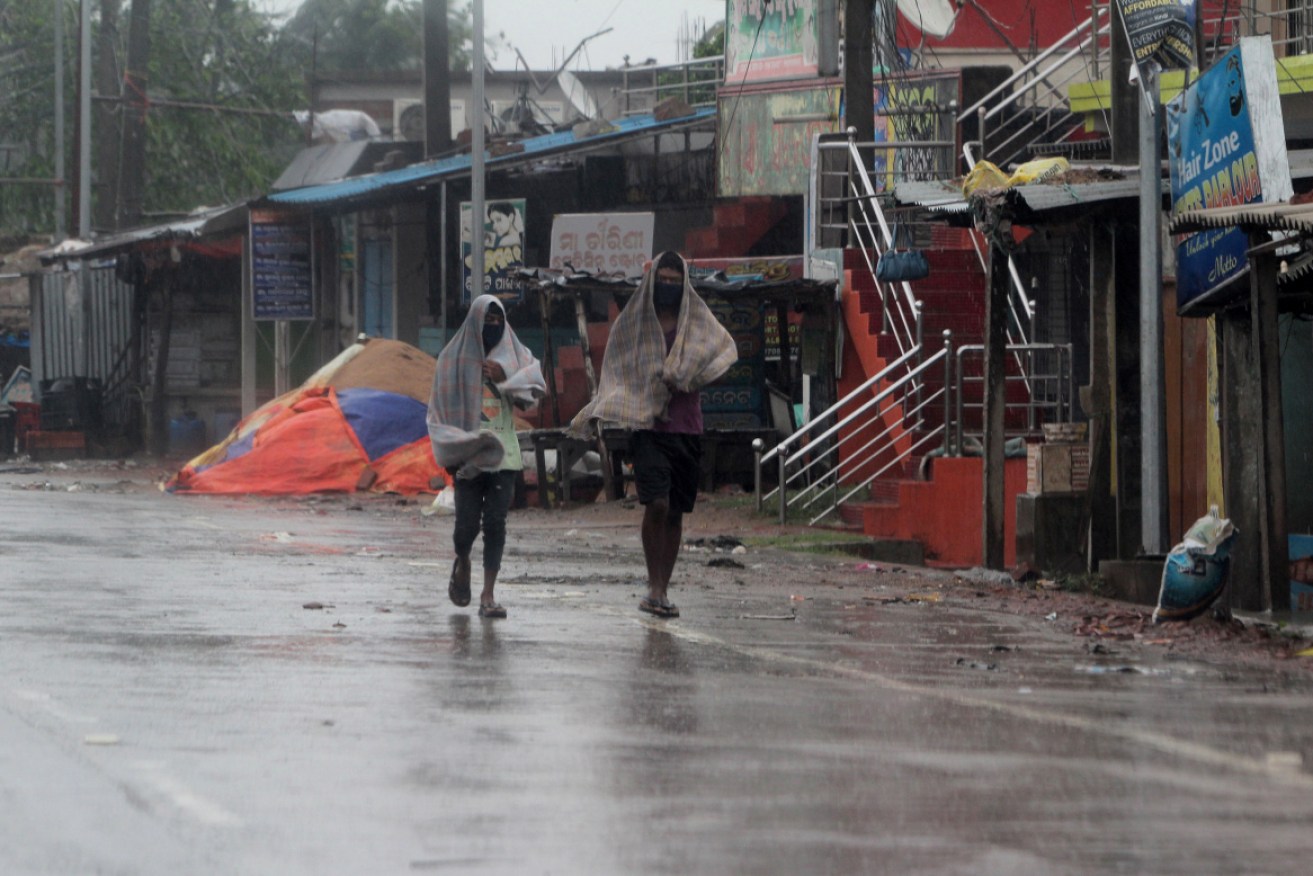 Locals walk in heavy rain and wind as cyclone Amphan approaches the Odisha coast in India on 20 May.