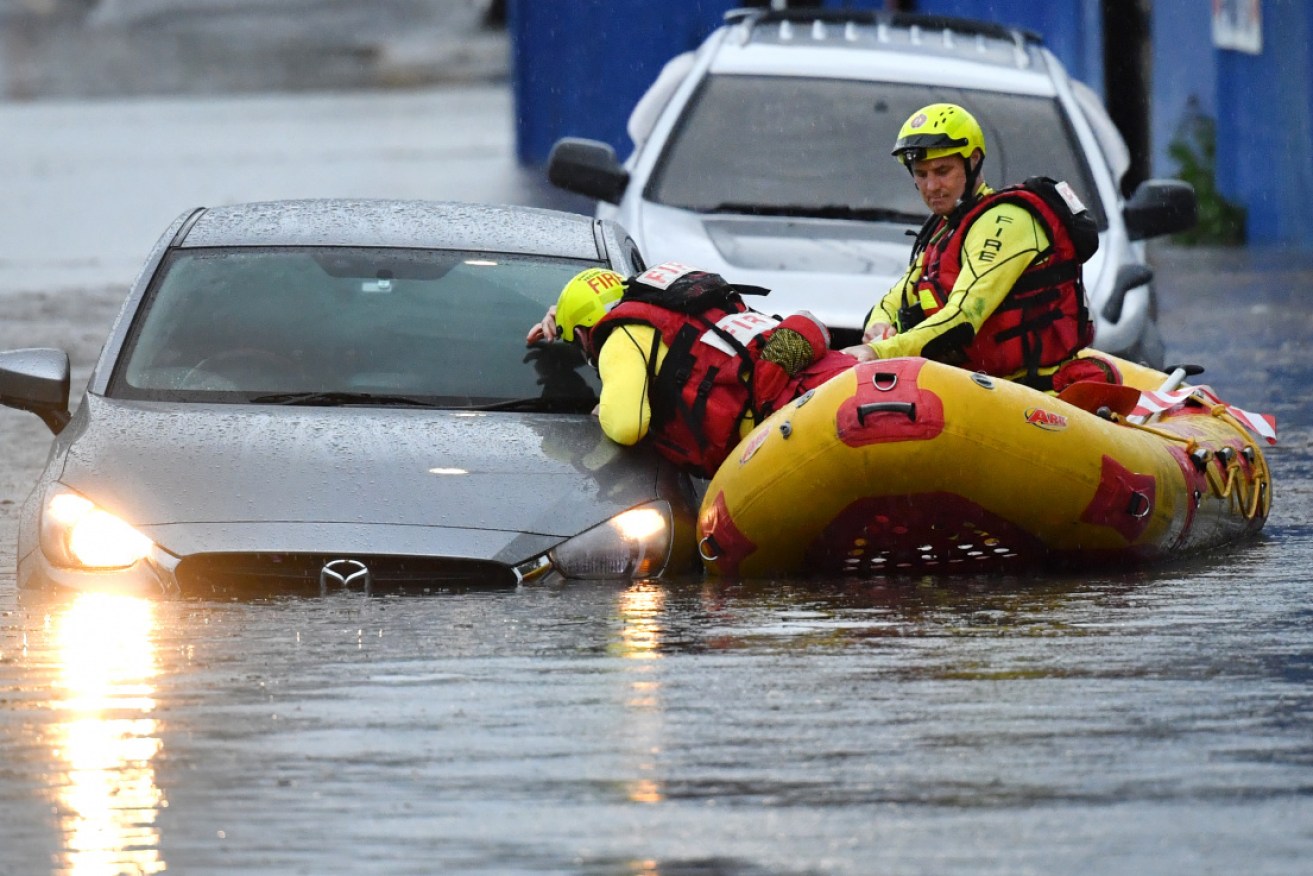 Queensland Fire and Emergency Services rescuers search flooded cars in Woolloongabba, Brisbane, after Tuesday's downpour.