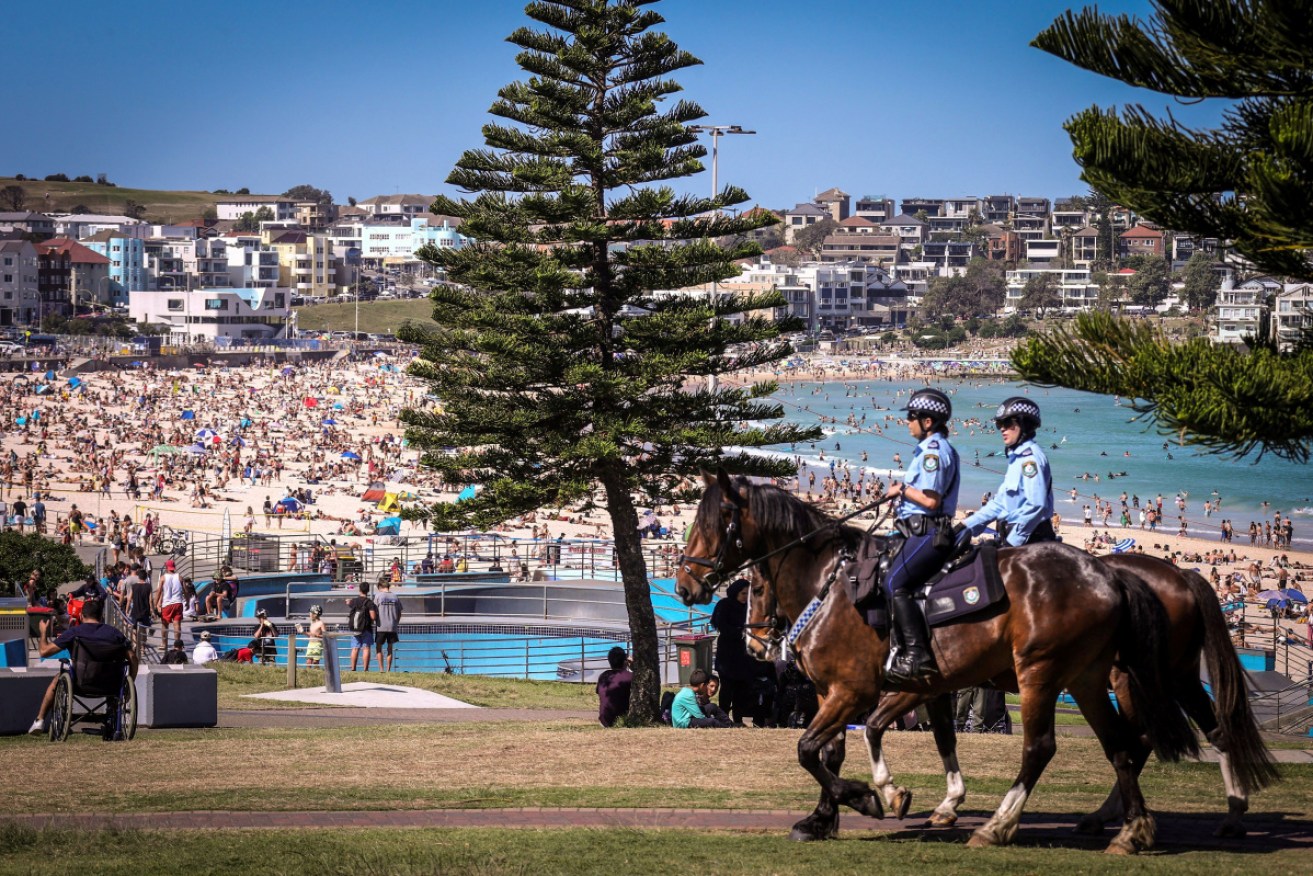 Police on horses patrol as people visit Bondi beach in Sydney.