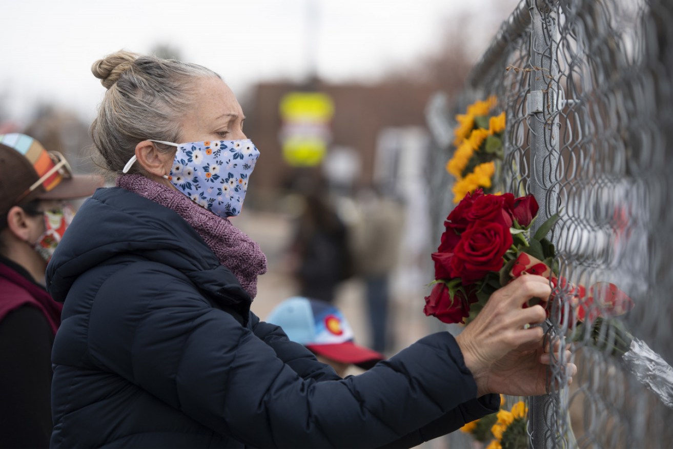 A woman adds flowers to a memorial outside the King Soopers shop in Boulder after the shooting.