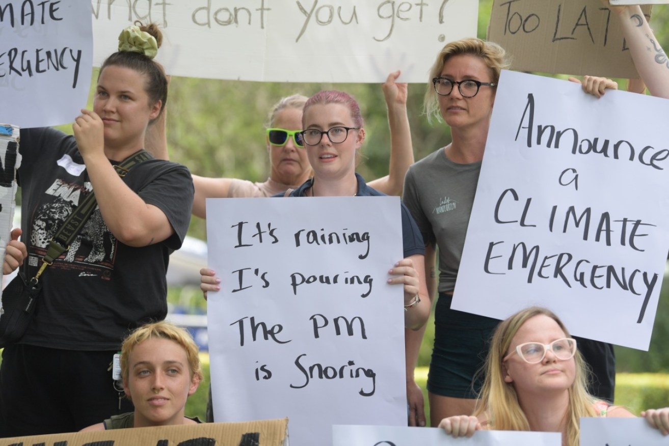Lismore residents hold signs as they wait for Prime Minister Scott Morrison during a visit to the city's Emergency Operations Centre on Wednesday.