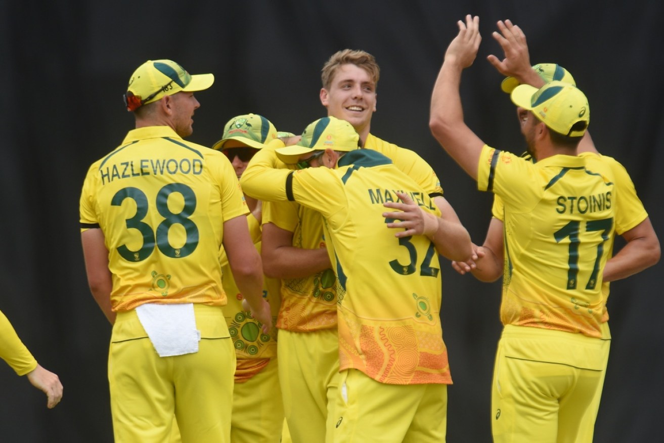 Teammates mob Cameron Green after taking a wicket in the first ODI at Riverway Stadium in Townsville on Sunday.