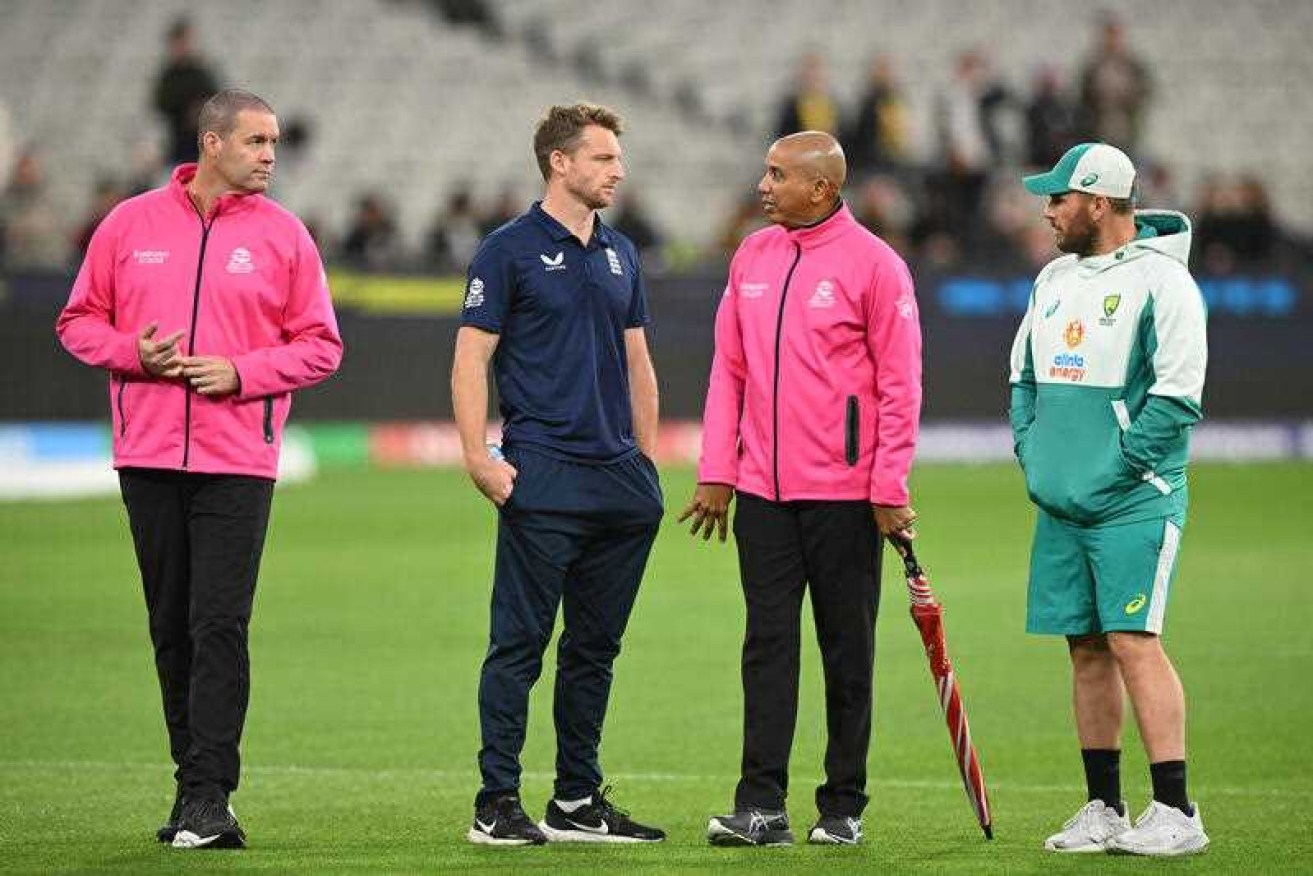 England captain Joss Butler [centre] and his Australian counterpart Aaron Finch talk to the umpires before their T20 clash at the MCG was abandoned. 