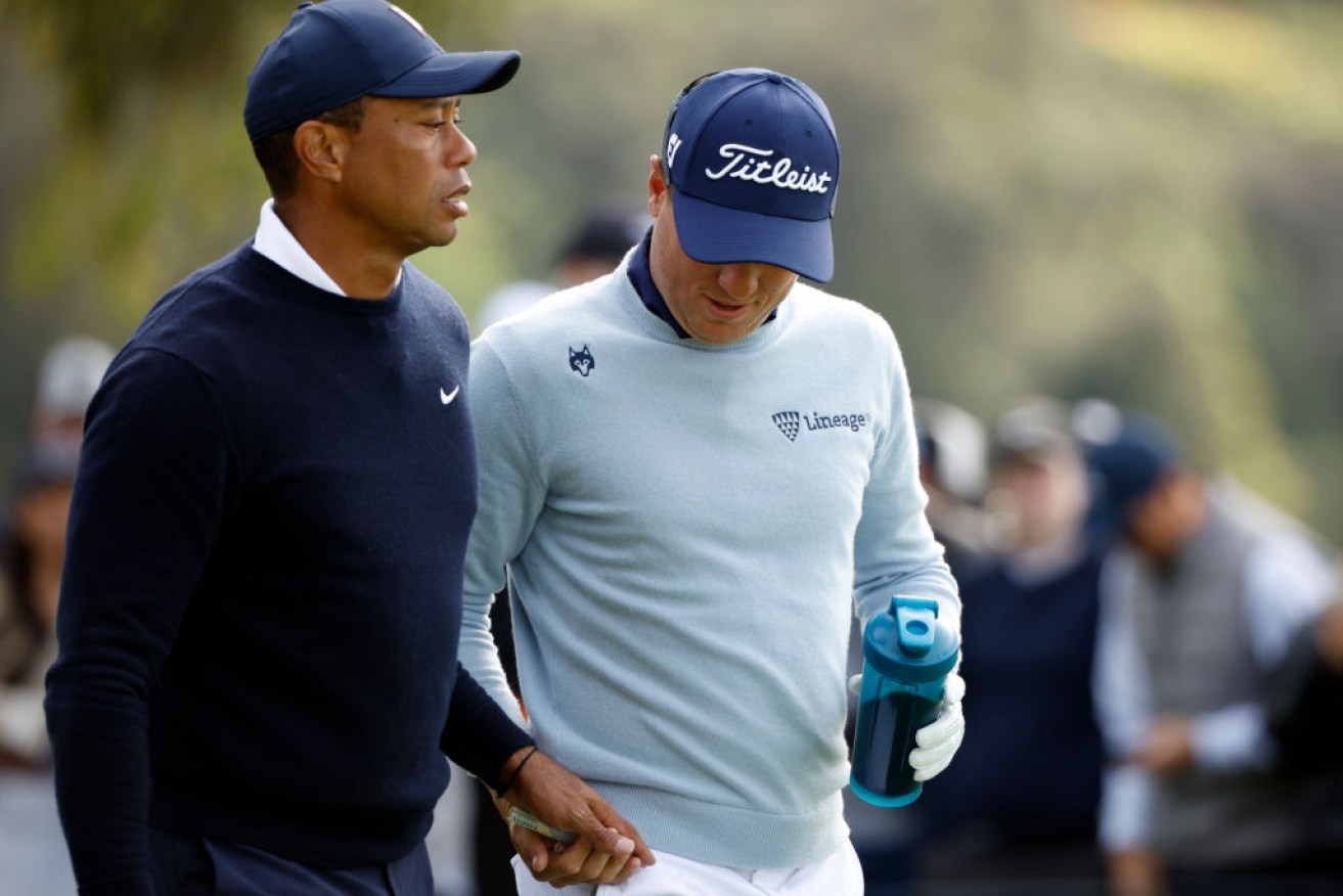 Tiger Woods hands a tampon to Justin Thomas while walking off the ninth tee at The Genesis Invitational in California.