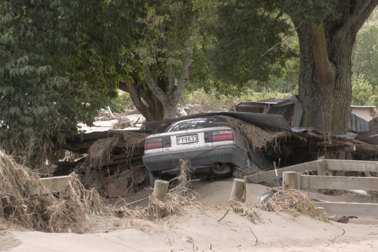 Smashed by Cyclone Gabrielle, this car lies half-buried in the debris of what was once a North Island home. <i>Photo: AAP</i>