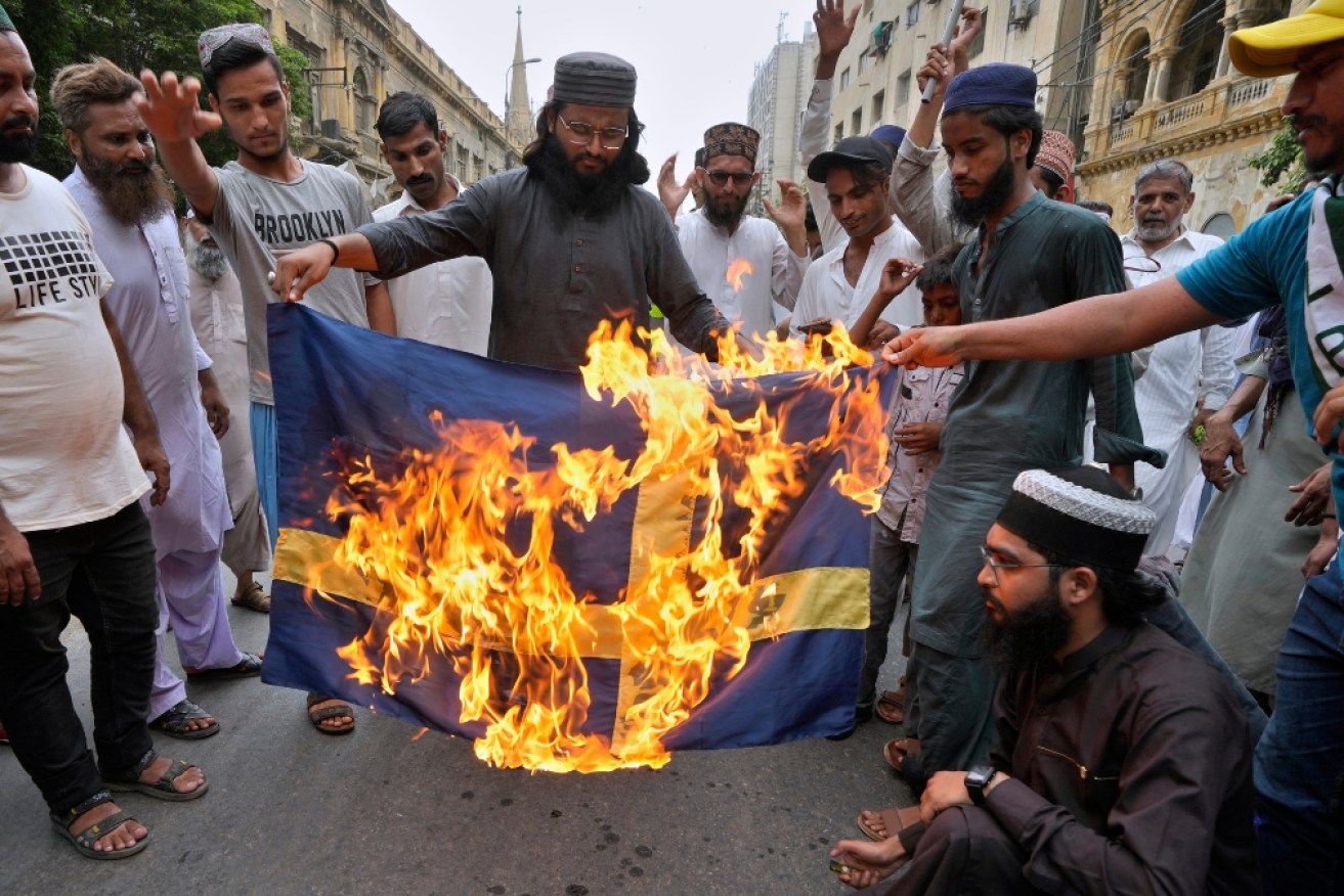 Supporters of a radical Islamist party in Pakistan burn the Swedish flag during a rally to condemn the burning of the Koran in Sweden.