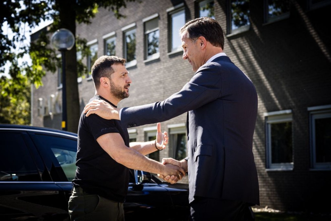 Ukrainian President Volodymyr Zelensky (L) and outgoing Dutch Prime Minister Mark Rutte shake hands during a visit to the Eindhoven Military Air Base. 