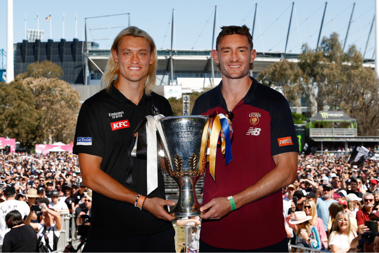 Magpies captain Darcy Moore (L) and Lions captain Harris Andrews with the premiership cup. 