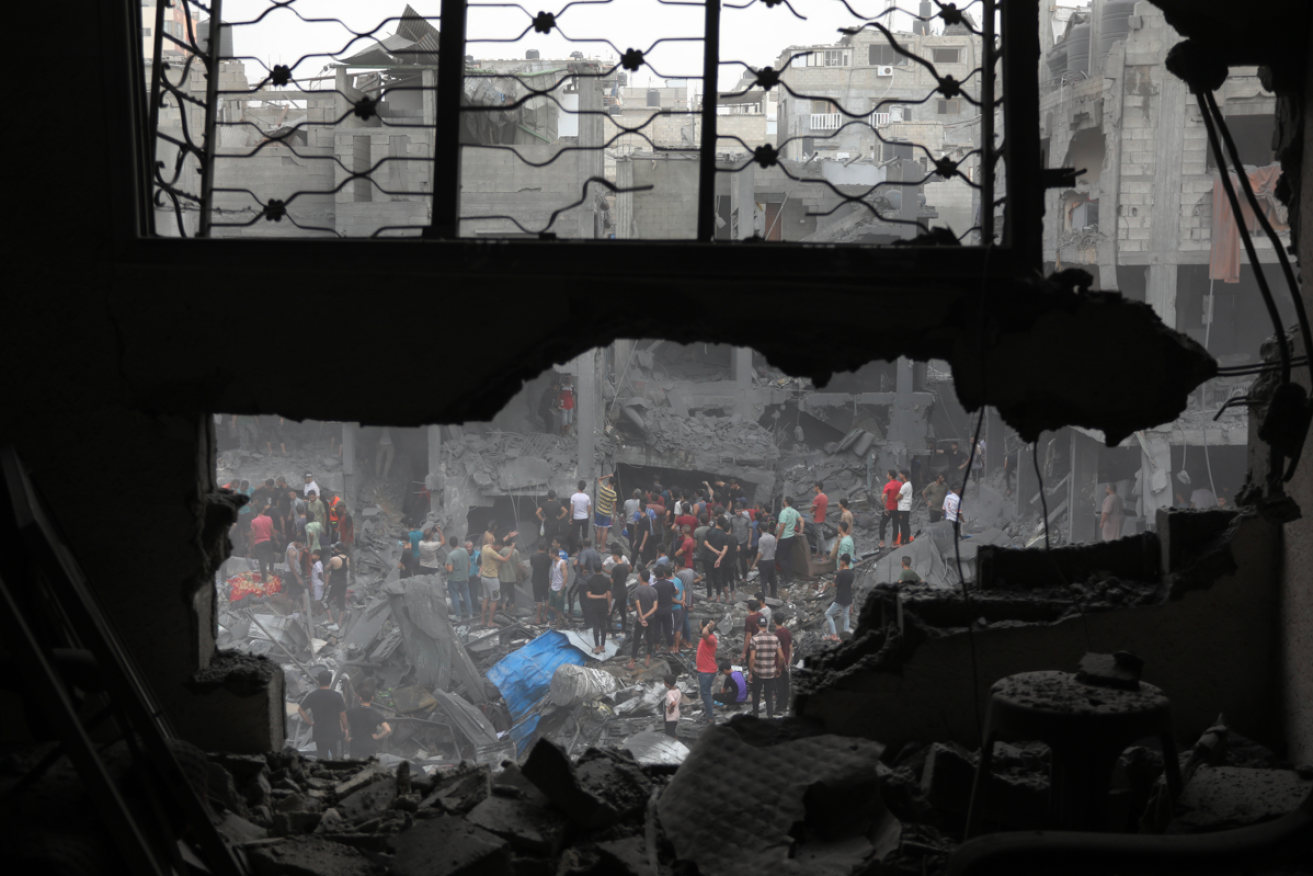 Framed through the window of one shattered home, Gazans search the rubble of another for bodies.