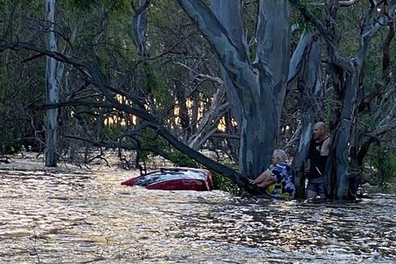 A man risked his life to help rescue a 74-year-old woman whose car was swept into flood waters.
