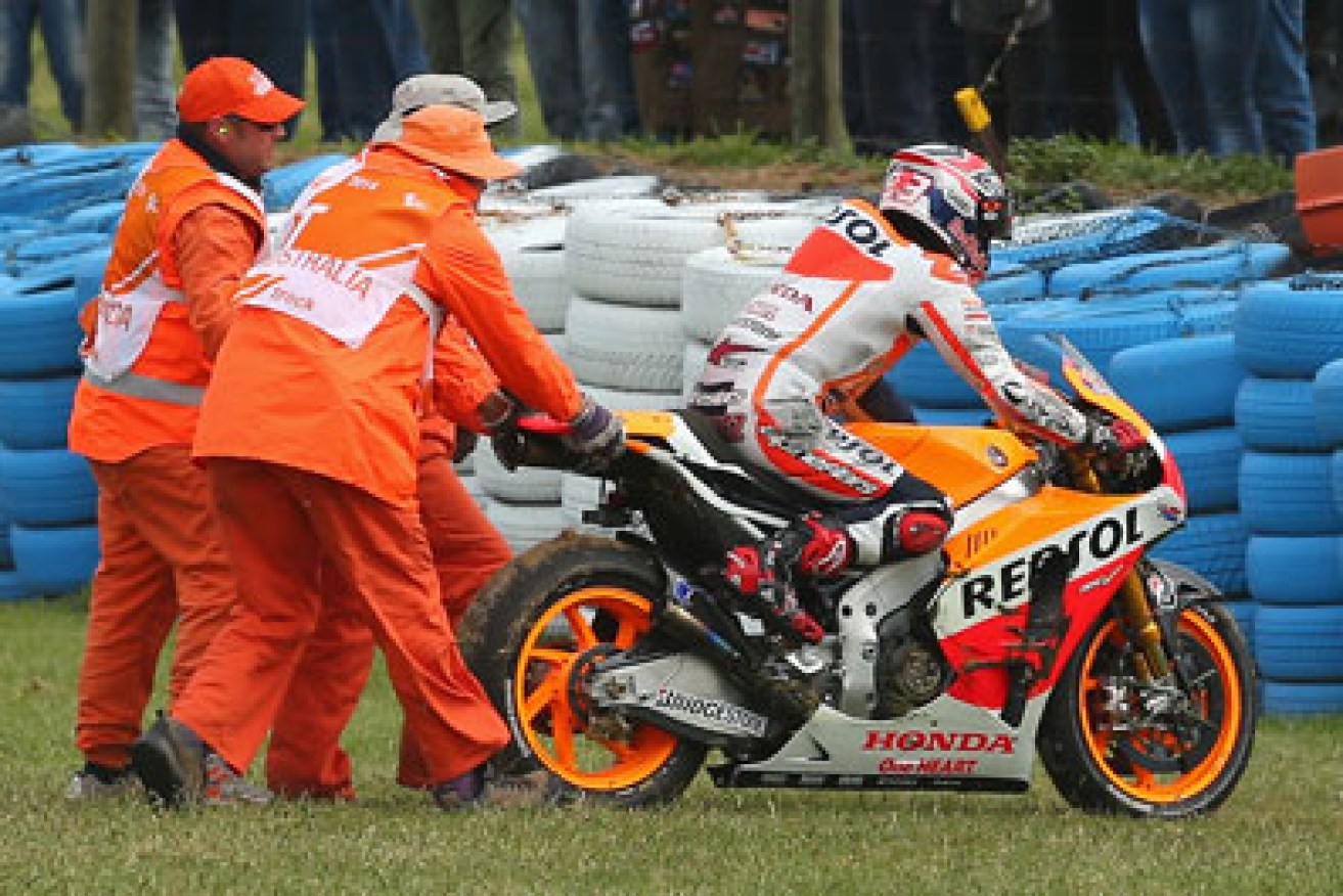 Marc Marquez is helped back on to the track after crashing out. Photo: Getty