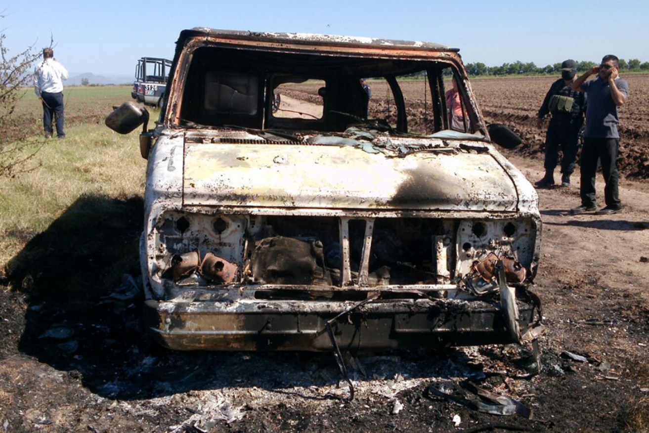 Mexican authorities inspect the burnt out van.