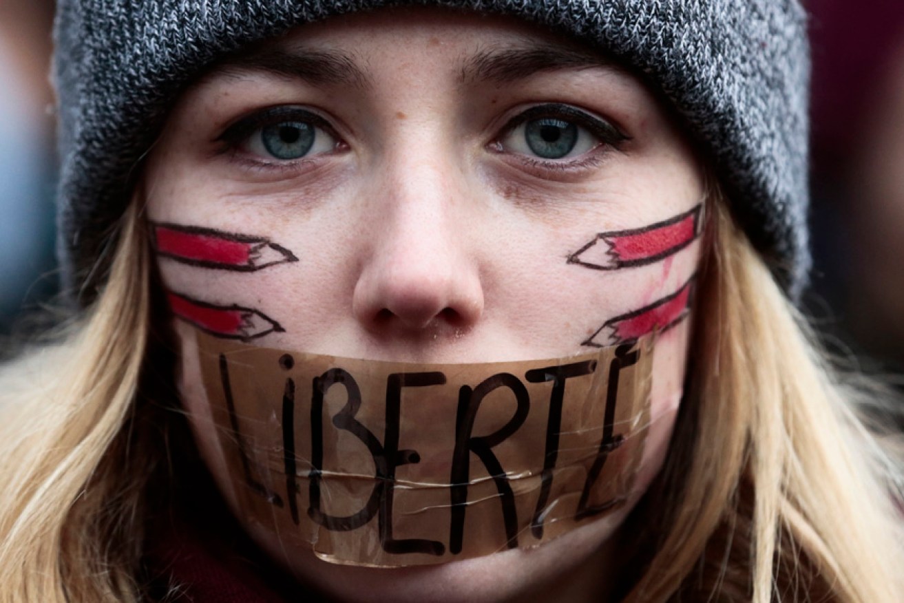 FILE - A woman has taped her mouth  displaying the word Freedom on the tape as she gathers with several thousand people in solidarity with victims of two terrorist attacks in Paris, one at the office of weekly newspaper Charlie Hebdo and another at a kosher market, in front of the Brandenburg Gate near the French embassy in Berlin, Sunday, Jan. 11, 2015.  (AP Photo/Markus Schreiber, File)