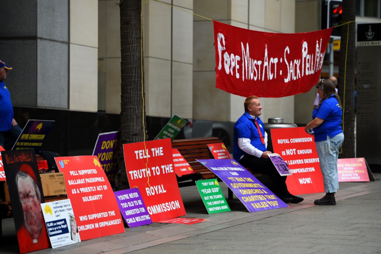 Demonstrators are seen with placards outside the commission in Sydney. Photo: AAP