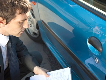 Insurance adjuster examining damage to car exterior
