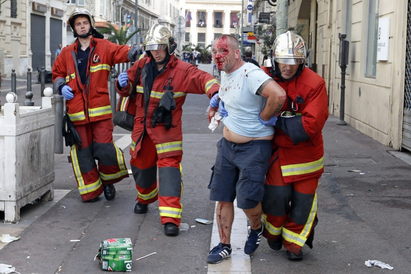  A man is taken away by emergency service workers after he was injured in clashes in downtown Marseille. Photo: AAP.