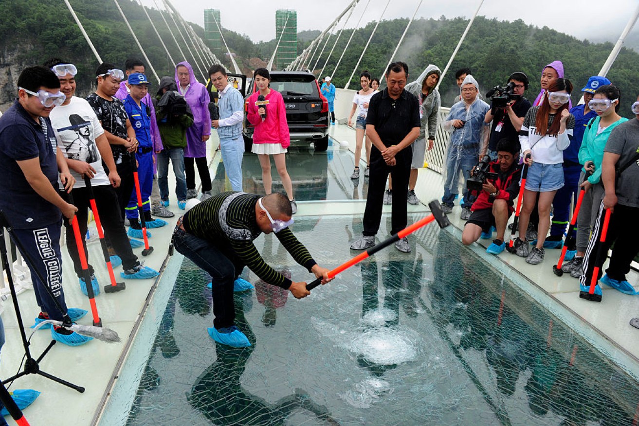 A visitor strikes the glass-bottomed bridge with a hammer for a safety test. Photo: Getty
