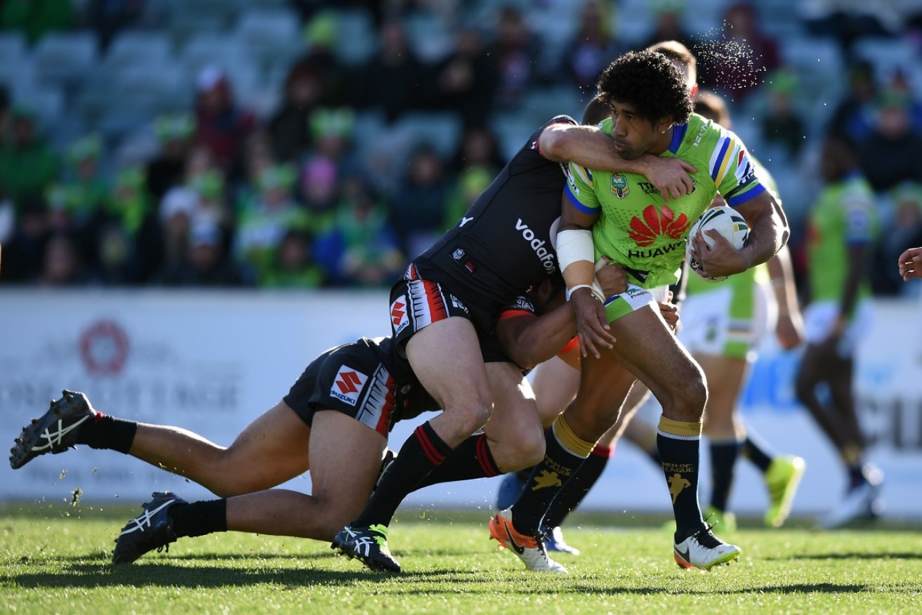 Iosia Soliola of the Raiders is tackled by Simon Mannering, and Bunty Afoa of the Warriors at GIO Stadium.