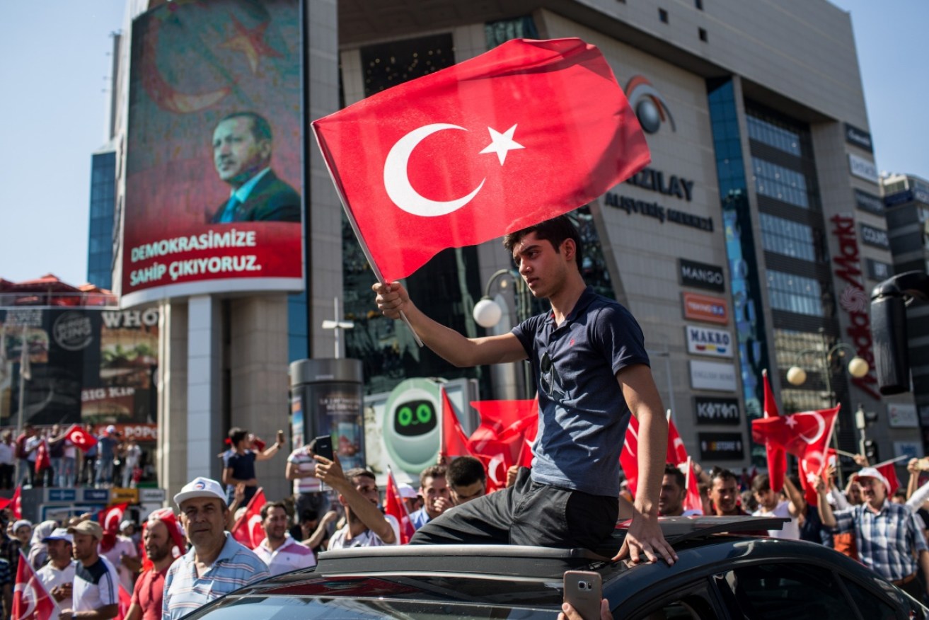 A man waves a Turkish flag from the roof of a car in reaction to the attempted military coup.
