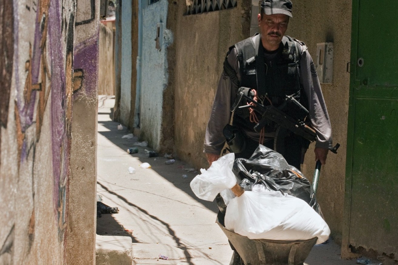 A police officer carries a wheelbarrow full of cocaine.
