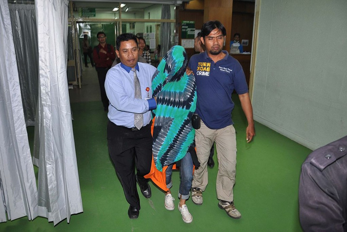 Sara Connor is escorted by Indonesian police officials.