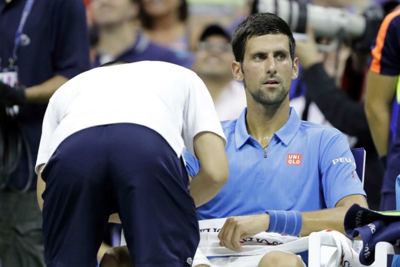 Novak Djokovic gets medical attention during his first round match against Jerzy Janowicz.