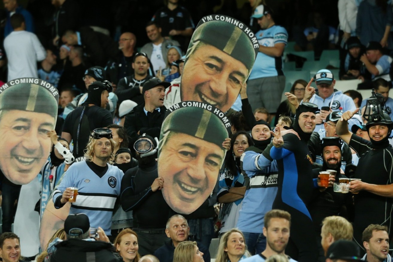 I'm coming home: Sharks fans in wetsuits hold up Harold Holt masks.