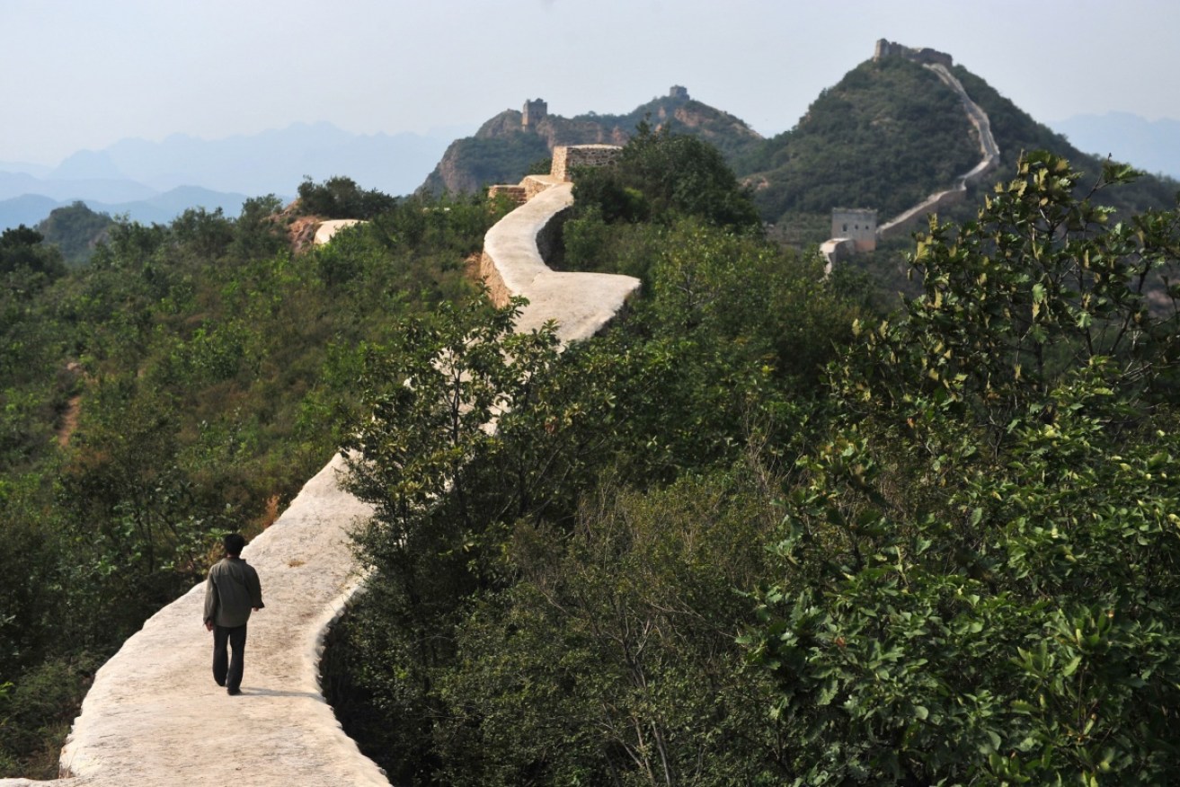 A Chinese farmer walks on a restored section of the Xiaohekou Great Wall.