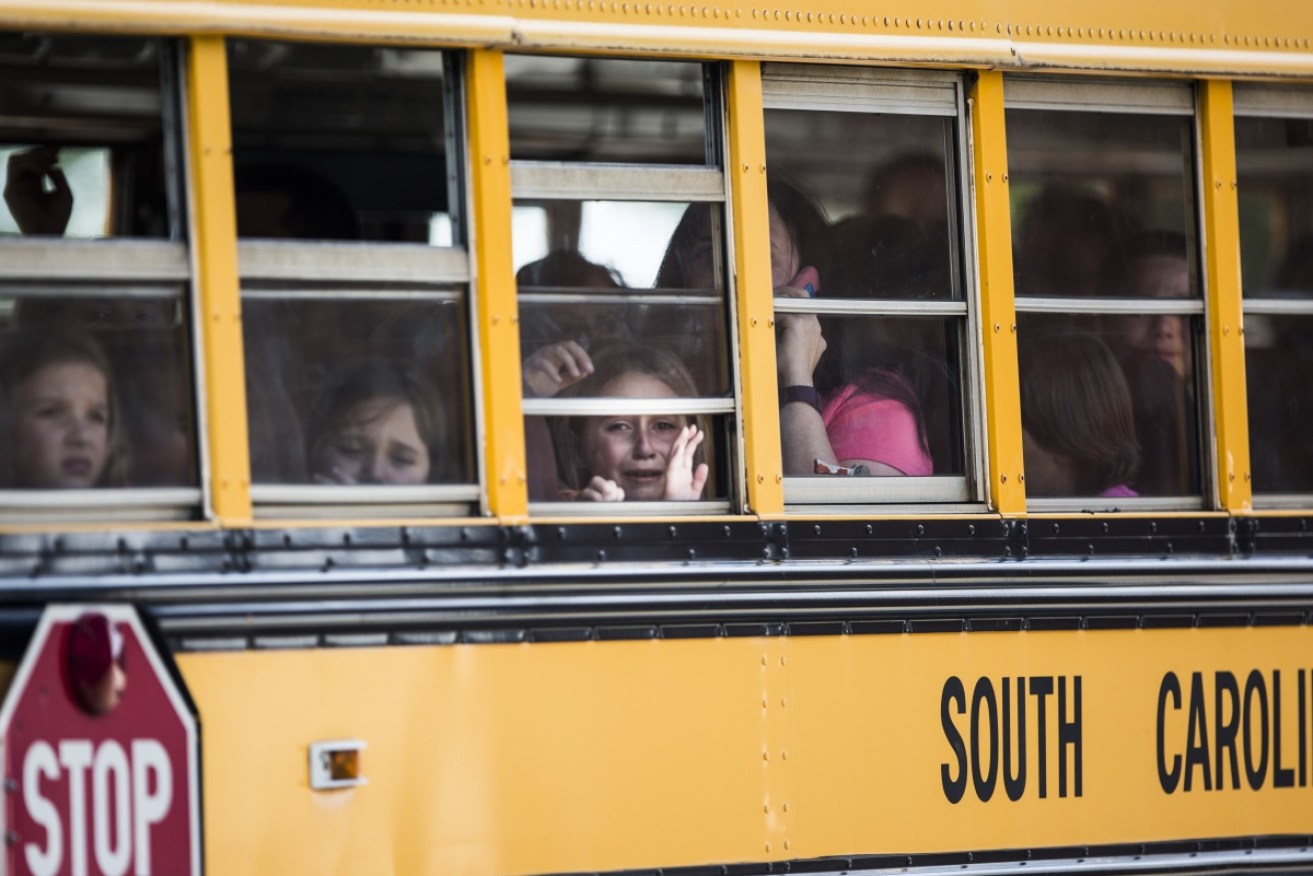 A young student looks out of the window of a school bus as she and her classmates are transported to a nearby church, following a shooting at Townsville Elementary in South Carolina.