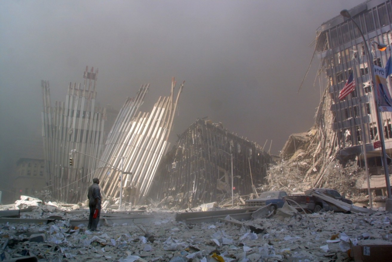 This 11 September 2001 file photo shows a man standing in the rubble, and calling out asking if anyone needs help, after the collapse of the first World Trade Center Tower.