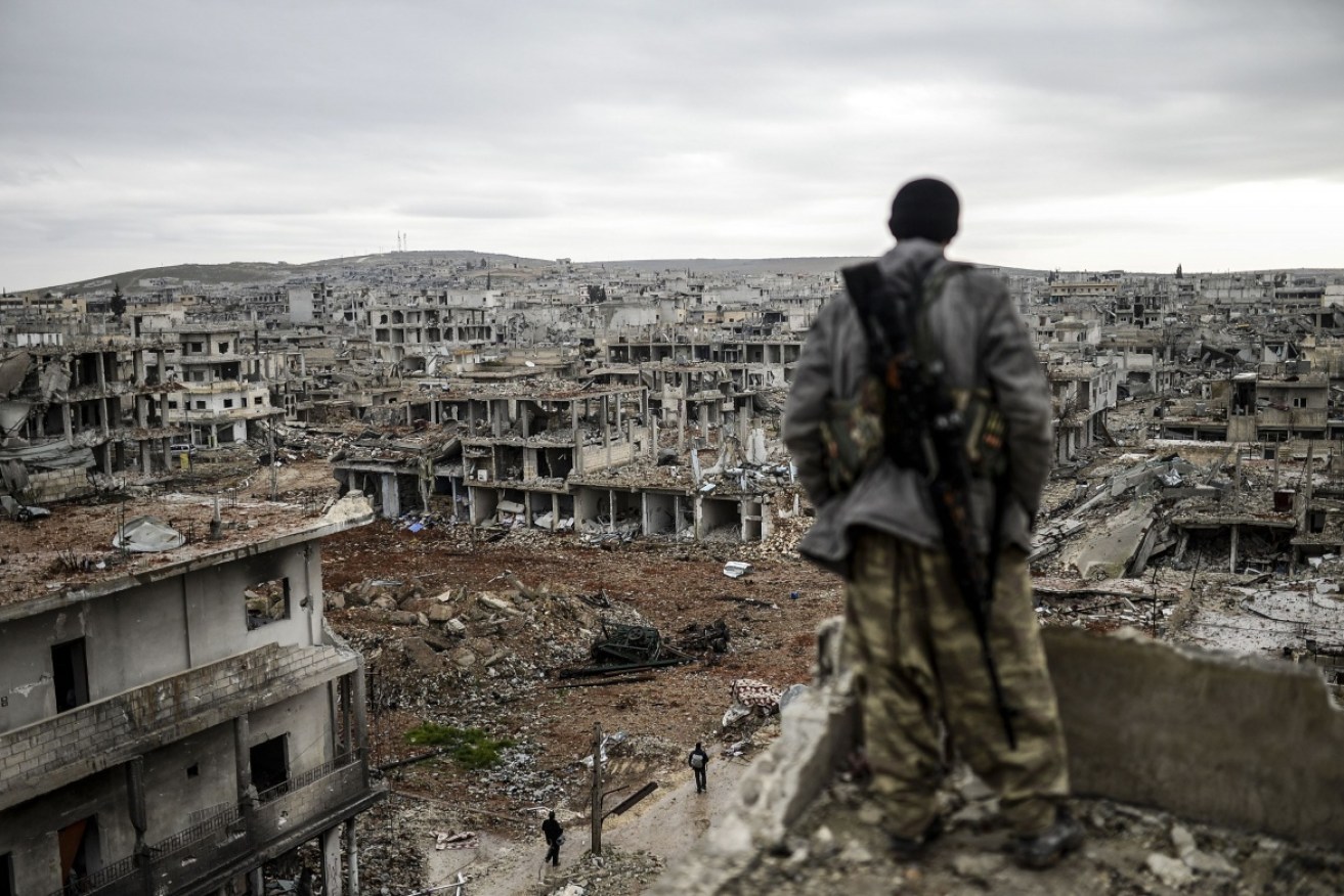A kurdish marksman overlooks the destroyed Syrian town of Kobane.