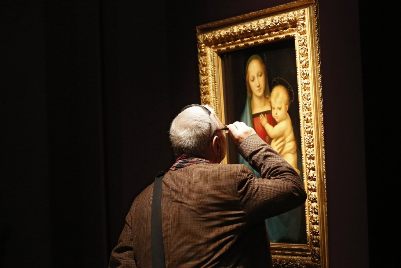 A man inspects Raphael's Madona Del Granduca at the Uffizi Gallery in Florence.