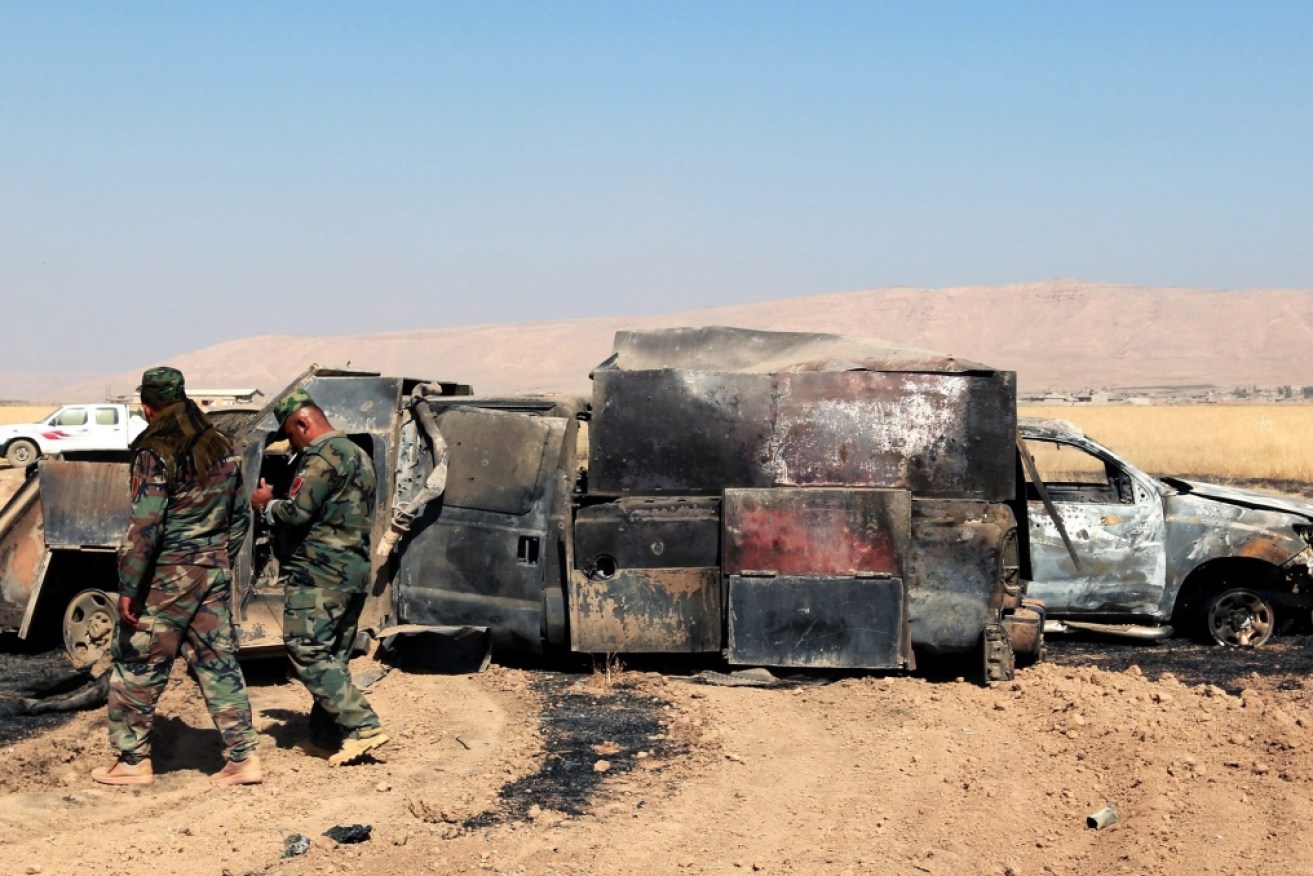 Peshmerga soldiers inspect a burnt truck used by Islamic State militants after heavy clashes with Iraqi forces in a fight to liberate villages. 