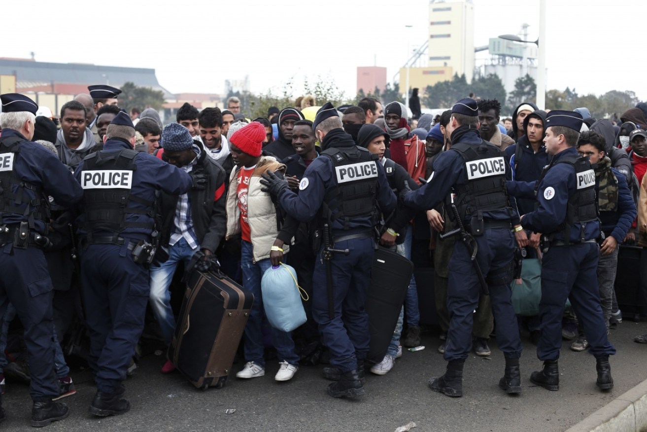 Riot police push back migrants as they line up to register at the 'Jungle' camp in Calais.
