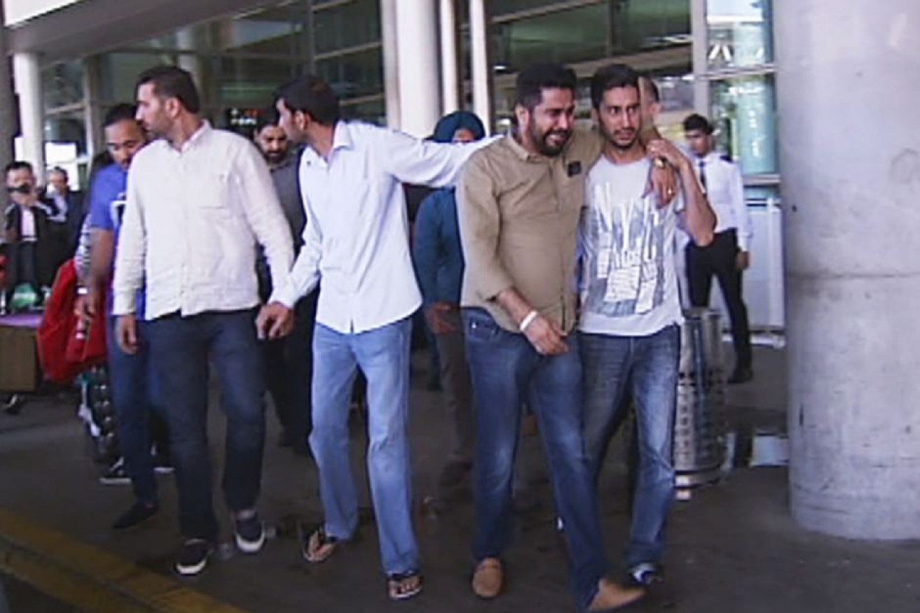 A distressed Amit Alisher (second from right) arrives in Brisbane.