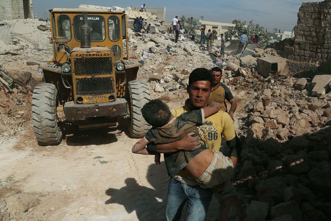 A man carries a Syrian kid after the Russian army carries out an airstrilke.