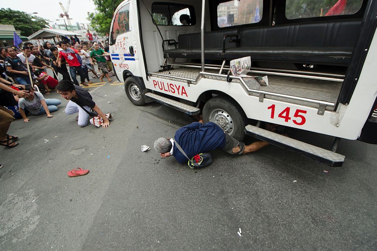A protester appears to be run over by a police van in Manila. 