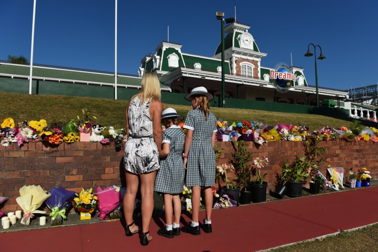 A family inspects the floral tribute out the front of the Dreamworld theme park. 