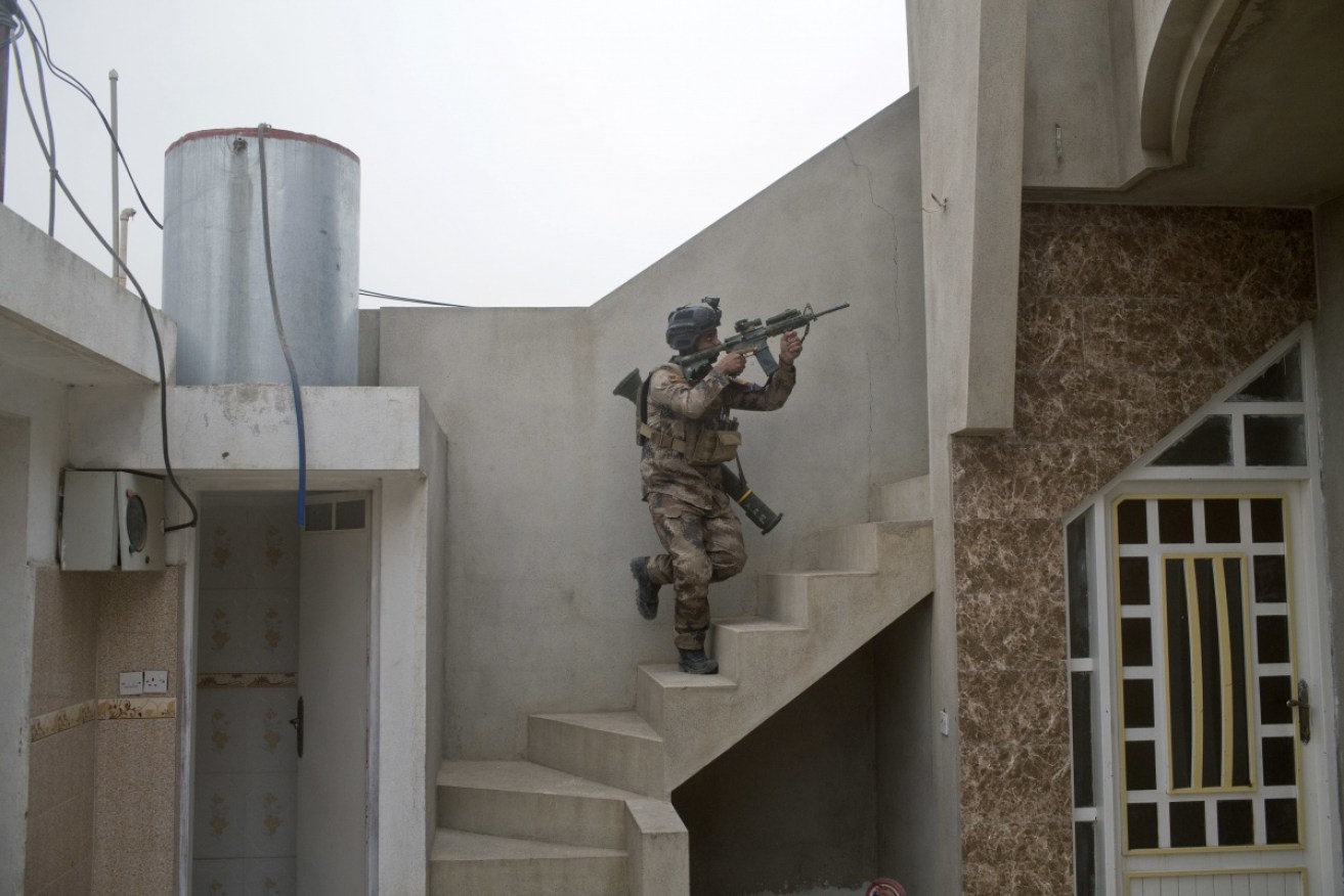 An Iraqi special forces soldier climbs up the stairs of a house as his unit searches for an Islamic State sniper position in Gogjali, an eastern district of Mosul. At least eight militants were killed.