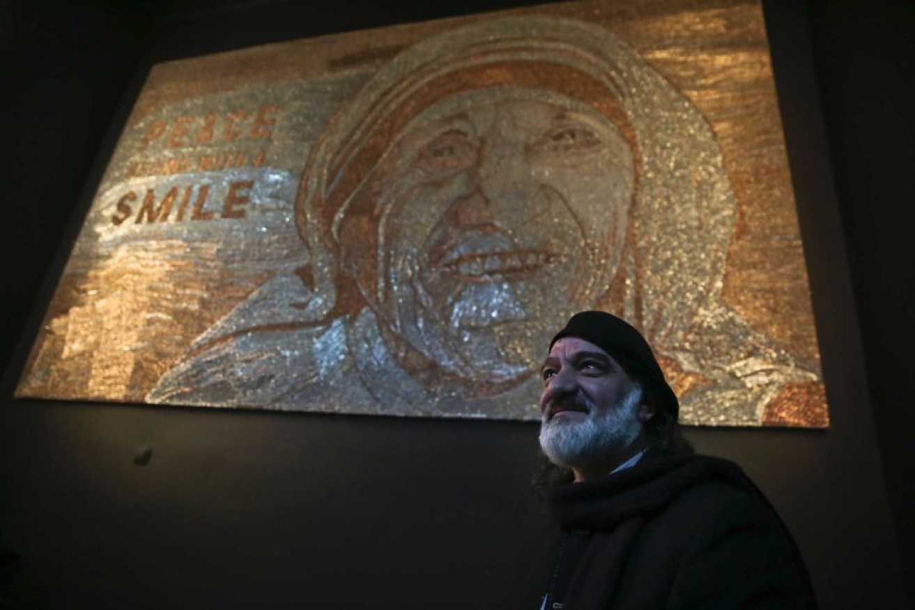 Artist Saimir Strati stands in front of his mosaic portrait of Mother Teresa.