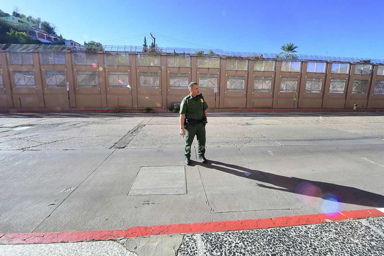 A US Border Patrol agent walking past the US-Mexico border wall in Arizona.