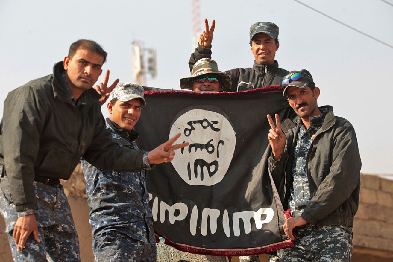 Iraqi soldiers display a captured Islamic State flag during the first stage of the assault on  Mosul in November.