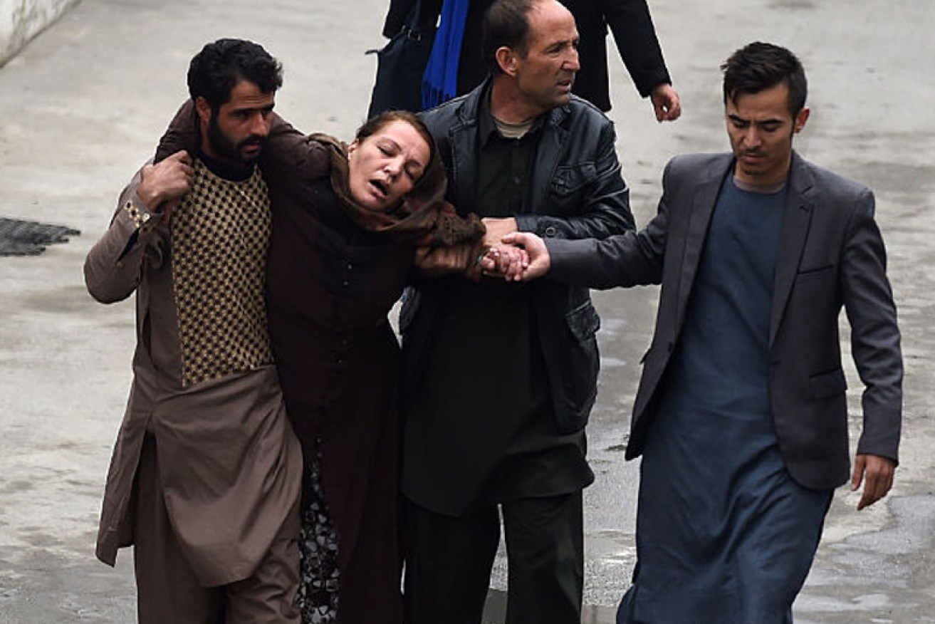 A woman is taken away from the suicide bombing in shock.