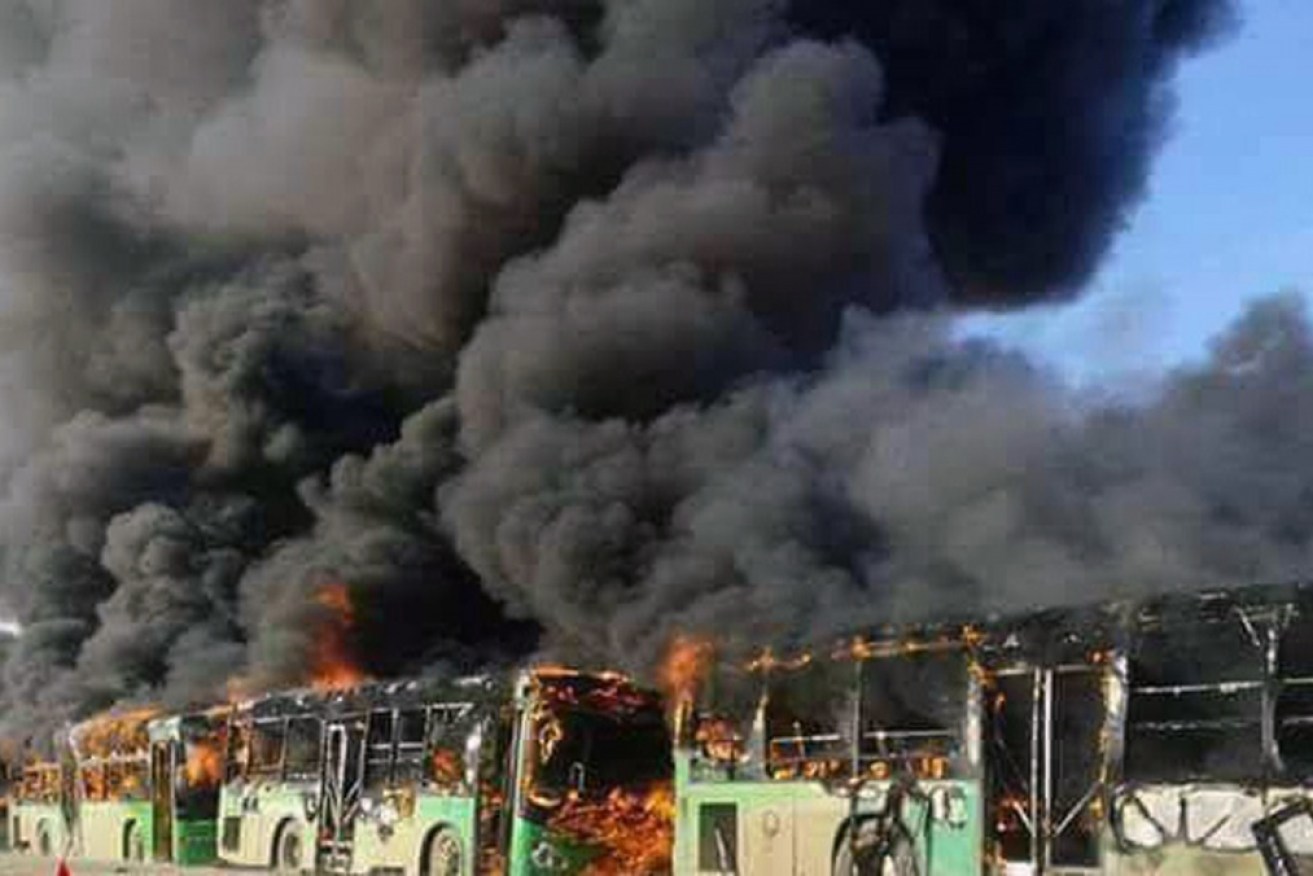 Smoke rises from green government buses in Idlib which had been assigned to take 1,200 sick and wounded people out of rebel-controlled villages. 