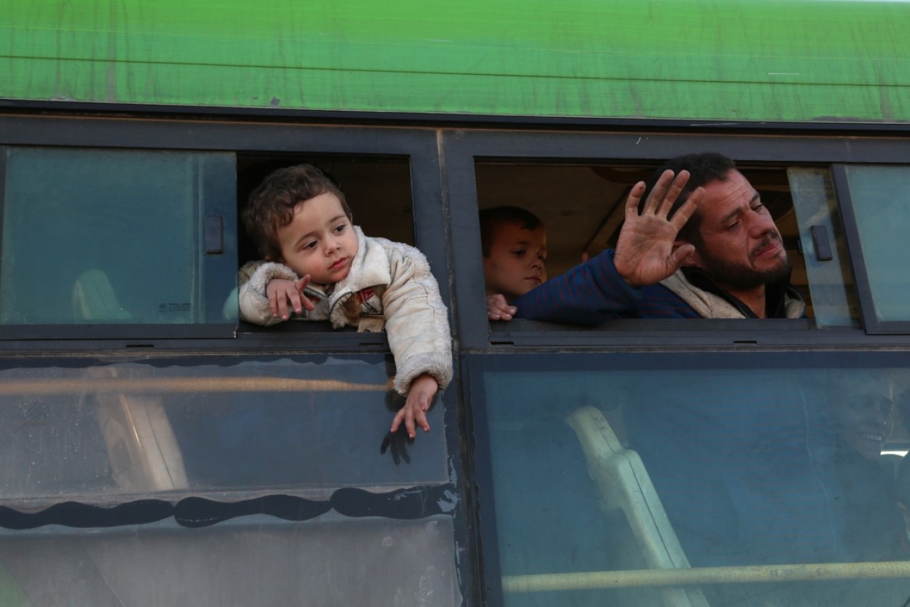 Civilians lean out of a bus window during the evacuation of Aleppo.